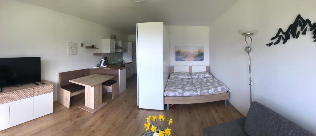 um pequeno quarto com uma cama, uma mesa e uma televisão em Seestern Strobl em Strobl