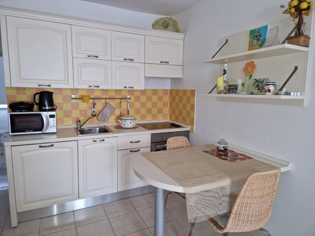 eine Küche mit weißen Schränken, einem Tisch und einem Waschbecken in der Unterkunft Studio apartman Altea in Stinica