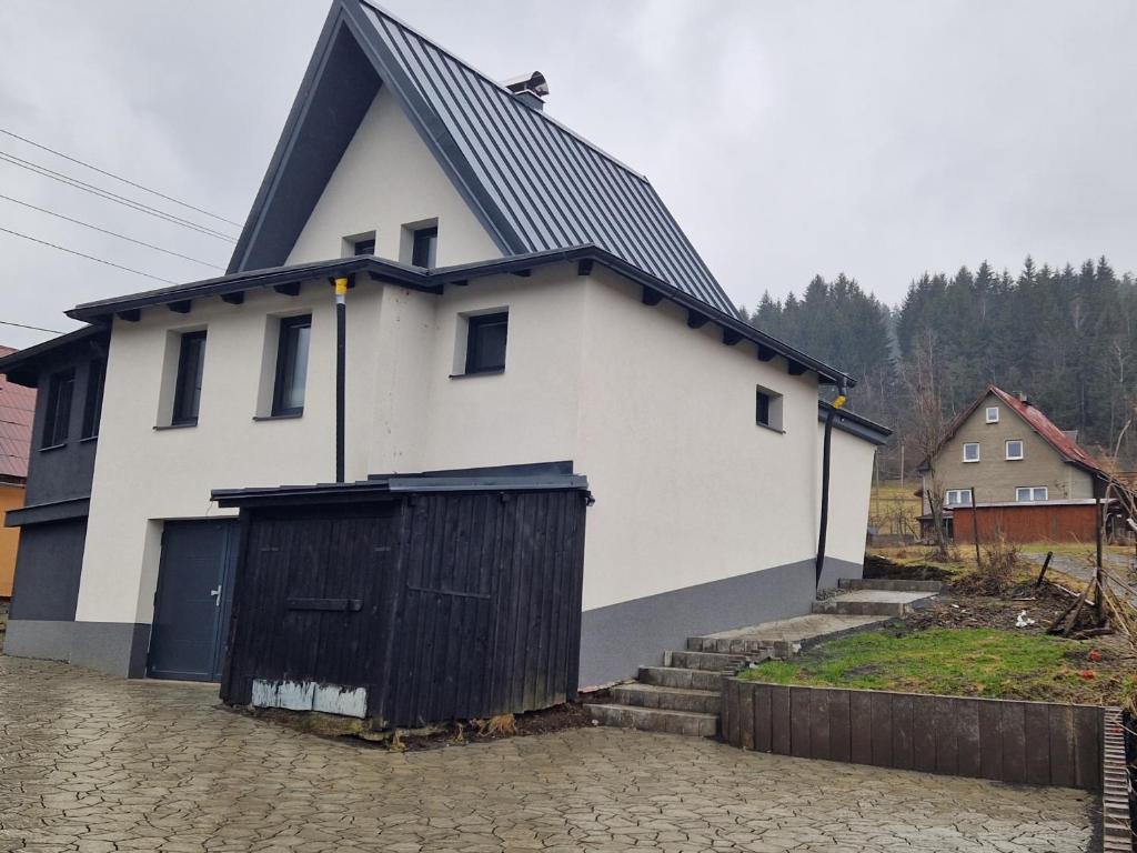 een wit huis met een zwart dak en een poort bij Objevte krásu Beskyd , navštivte chatu Lojza in Staré Hamry