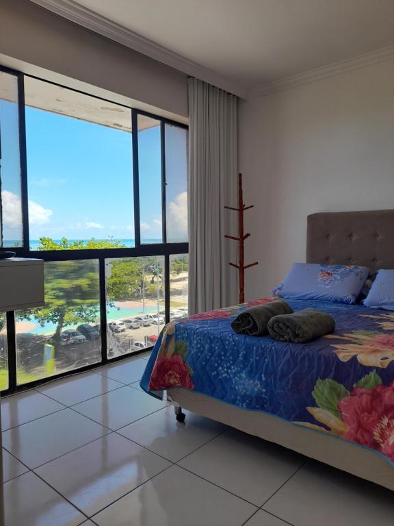 um quarto com uma cama e vista para a praia em dúplex beira-mar em Maceió