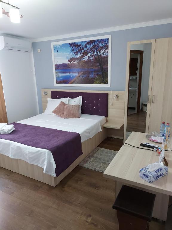 een slaapkamer met een groot bed en een bureau bij CASA IV in Vama Veche