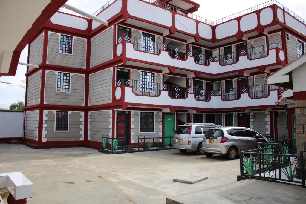 um edifício vermelho e branco com carros estacionados num parque de estacionamento em Furnished Apartments in Nairobi 14km from Jomo Kenyatta International Airport and SGR em Embakasi
