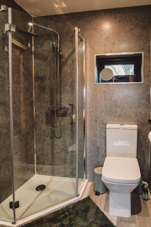 a bathroom with a shower and a toilet at Luxury Glamping Cabin with Outdoor Bath on Cornish Flower Farm in Truro