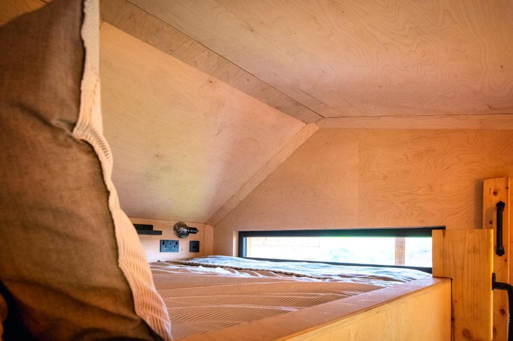 a bed in a small room with a window at Luxury Glamping Cabin with Outdoor Bath on Cornish Flower Farm in Truro