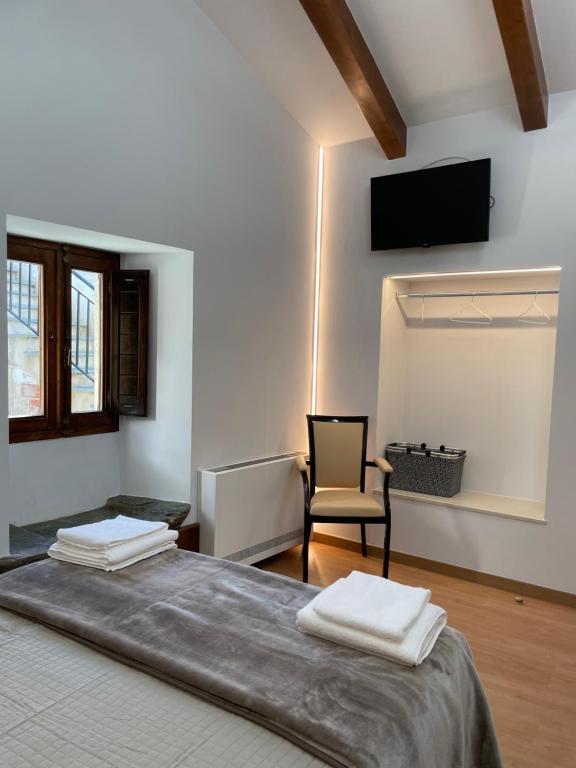 a bedroom with a bed with a chair and a television at Hostal A Cantina de Renche in Renche