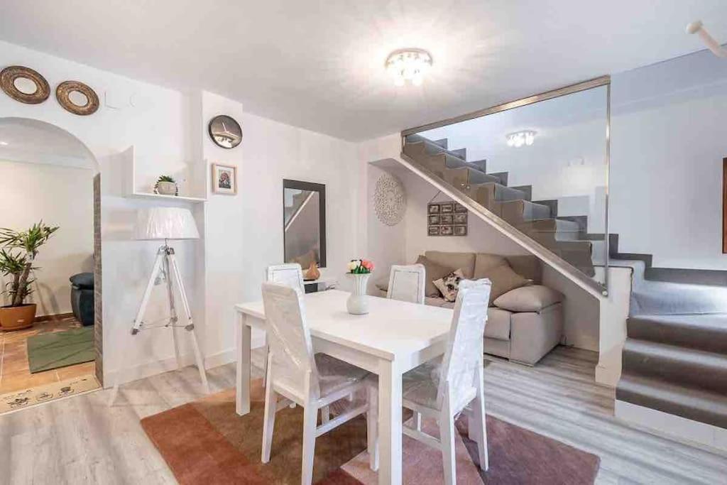 uma sala de jantar com uma mesa branca e uma escada em Entire house close to Albaicin and the city center em Granada