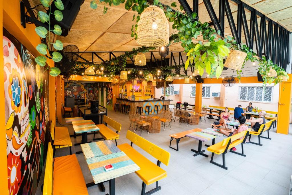 a restaurant with yellow tables and chairs and people sitting at tables at Nacho Hostel Cebu in Bulacao