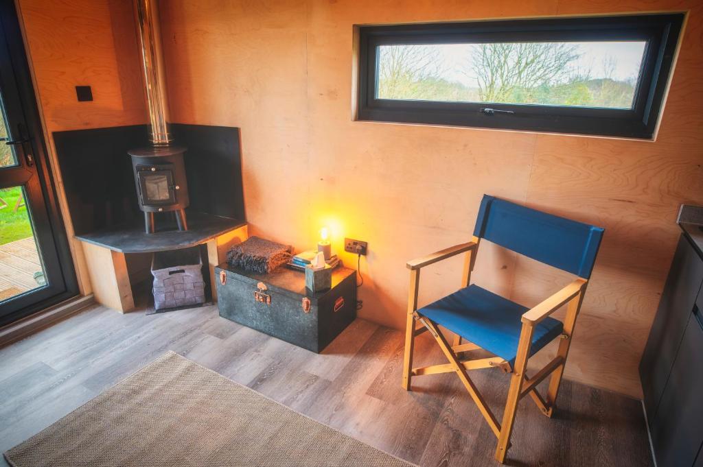 a room with a chair and a wood stove at Luxury Glamping Cabin with Outdoor Bath on Cornish Flower Farm in Truro
