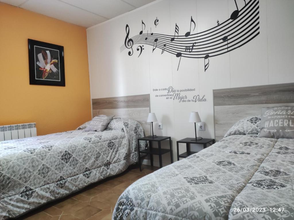 2 camas en una habitación con notas musicales en la pared en Acogedor, en Zaragoza