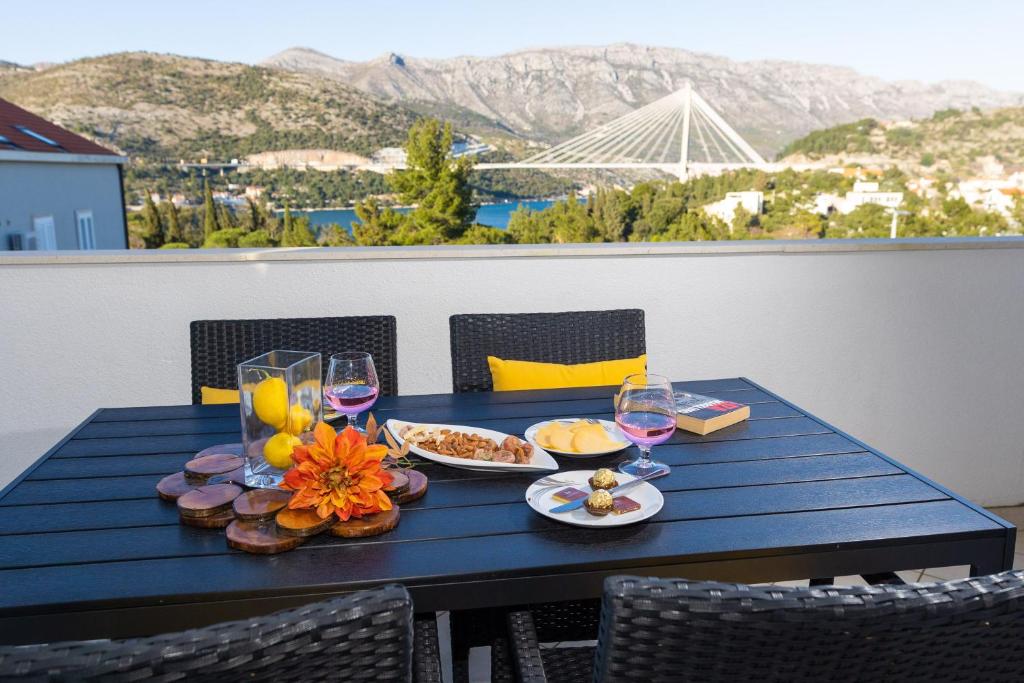 una mesa azul con comida y copas de vino en el balcón en Villa Erna, en Dubrovnik