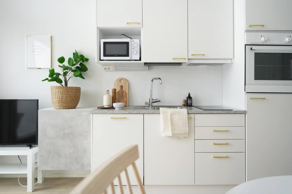 a white kitchen with a sink and a microwave at Maple Loft Apartment 