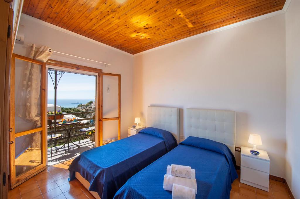 a bedroom with a blue bed and a balcony at Casa la noce Positano in Positano