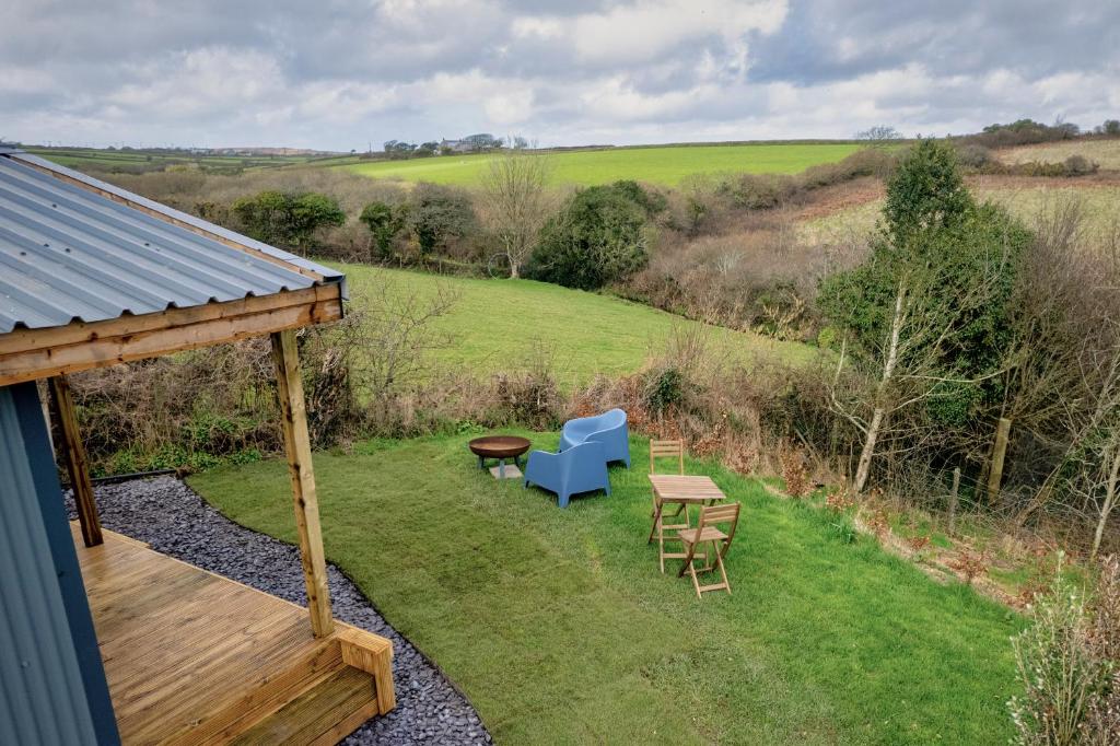 a garden with a table and chairs and a bench at Luxury Glamping Cabin with Outdoor Bath on Cornish Flower Farm in Truro