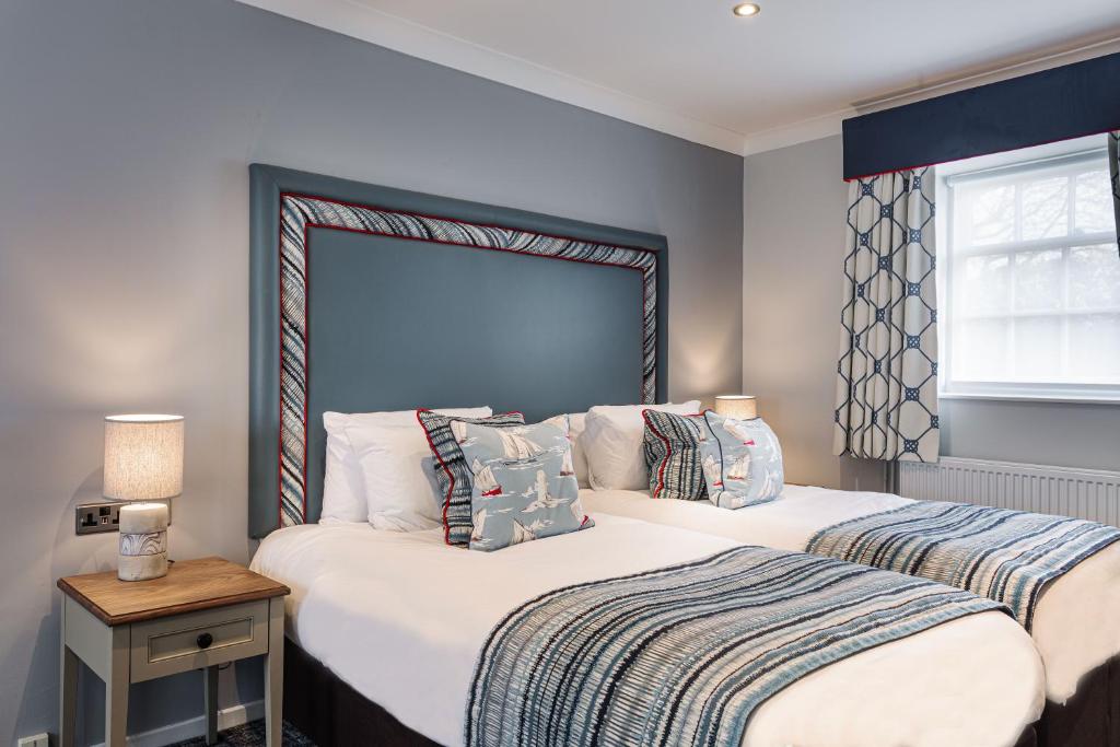 a bedroom with two beds and a window at The Manor Coastal Hotel & Inn, Blakeney - part of The Coaching Inn Group in Blakeney