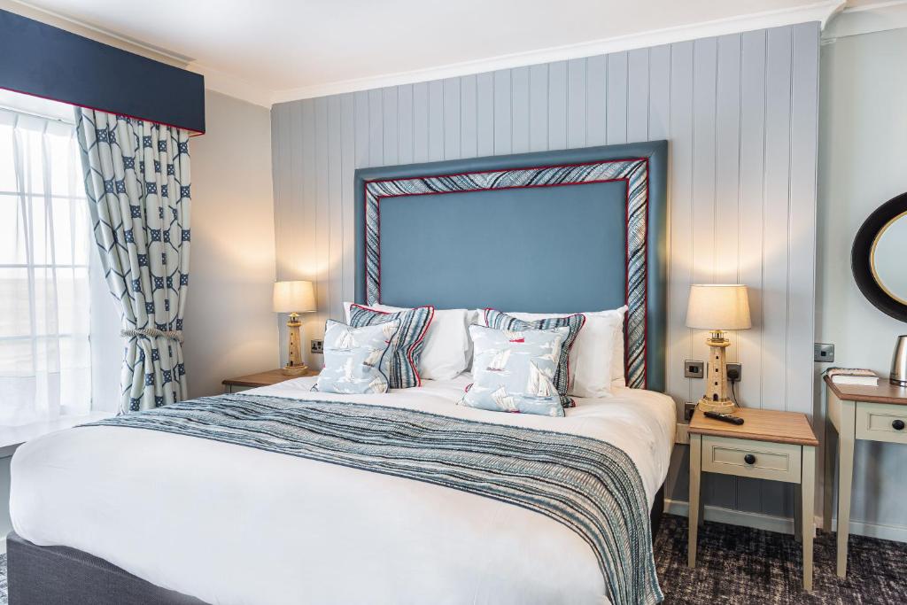 a bedroom with a large white bed with pillows at The Manor Coastal Hotel & Inn, Blakeney - part of The Coaching Inn Group in Blakeney