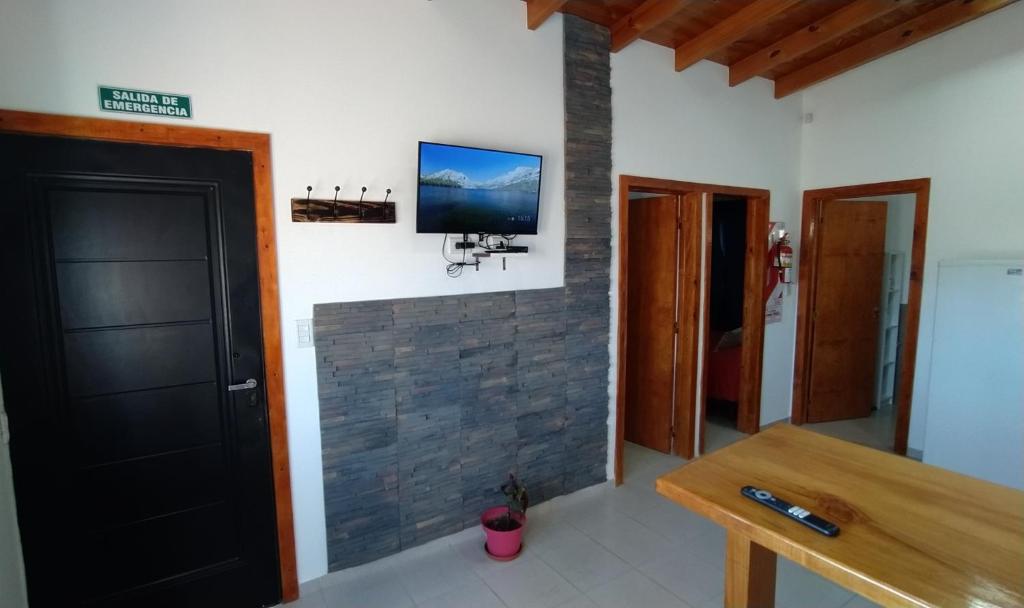 een kamer met een tv aan een bakstenen muur bij Cabaña los Hielos in El Calafate