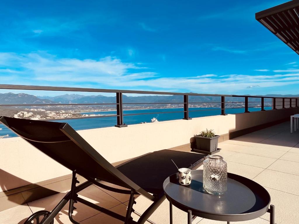 um pátio com uma mesa e uma cadeira na varanda em splendide T3 neuf de haut standing en toit terrasse dominant le golfe d'Ajaccio, terrasse de 70m2 em Ajaccio