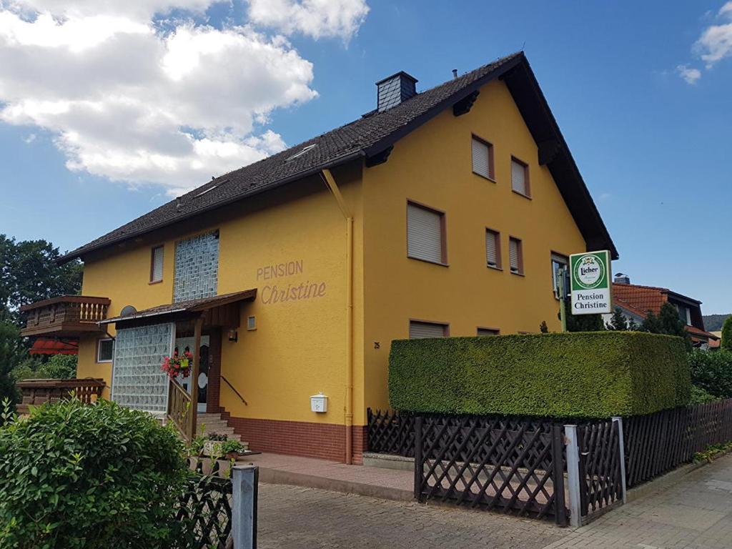 Pension Christine في Neu-Anspach: مبنى اصفر امامه لافته