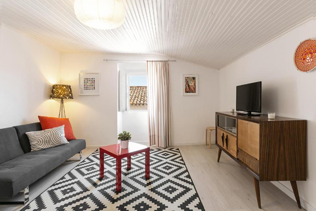 ein Wohnzimmer mit einem Sofa und einem TV in der Unterkunft Ana's House in Óbidos