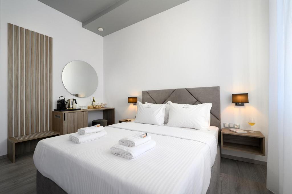 une chambre avec un grand lit blanc avec deux serviettes dessus dans l'établissement Amalphi Corfu City Living by Konnect, à Corfou