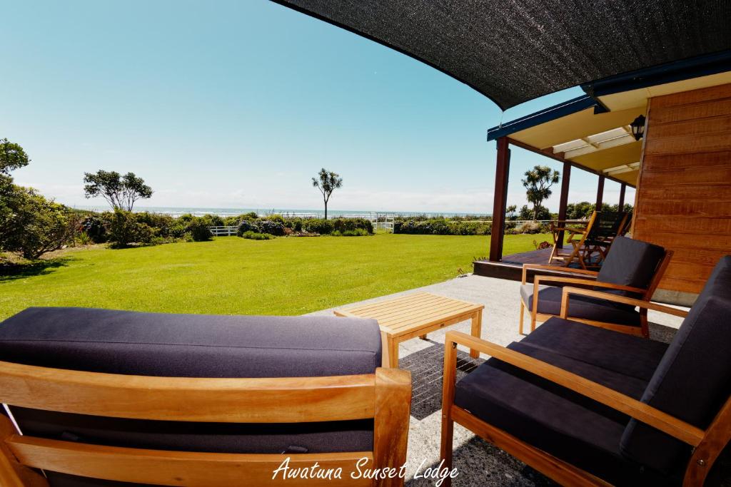 um alpendre com cadeiras, uma mesa e um campo em Awatuna Sunset Lodge em Hokitika