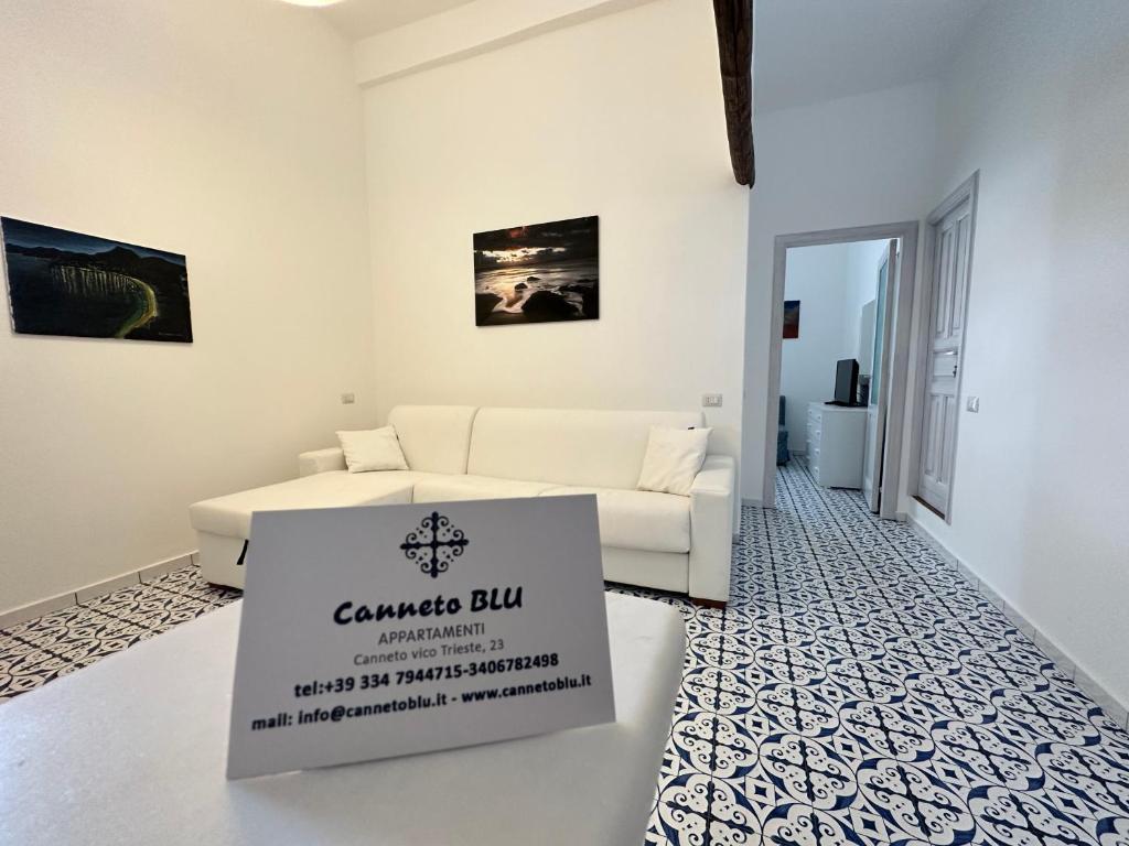 una sala de estar blanca con sofá y un cartel en el suelo en CANNETO BLU, en Lipari