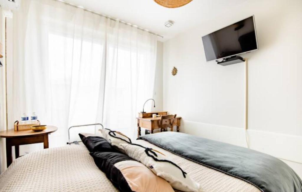 a bedroom with a bed and a flat screen tv at Chambres Élégance - Parc Bordelais in Bordeaux
