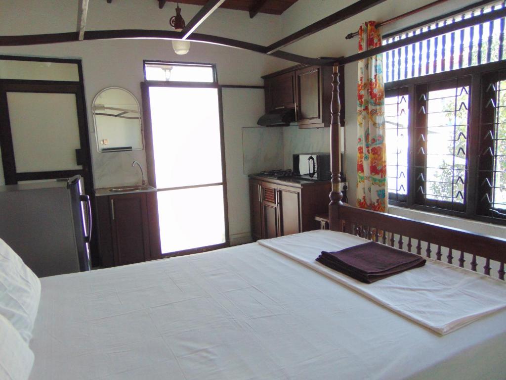 a bedroom with a large white bed and two windows at Horton Studios in Colombo