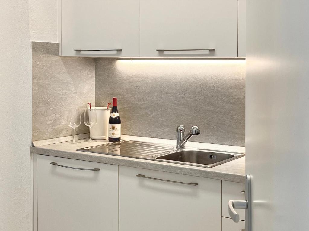 a kitchen with a sink and a bottle of wine at GuestHouse Lugano Center Apartments by LR in Lugano