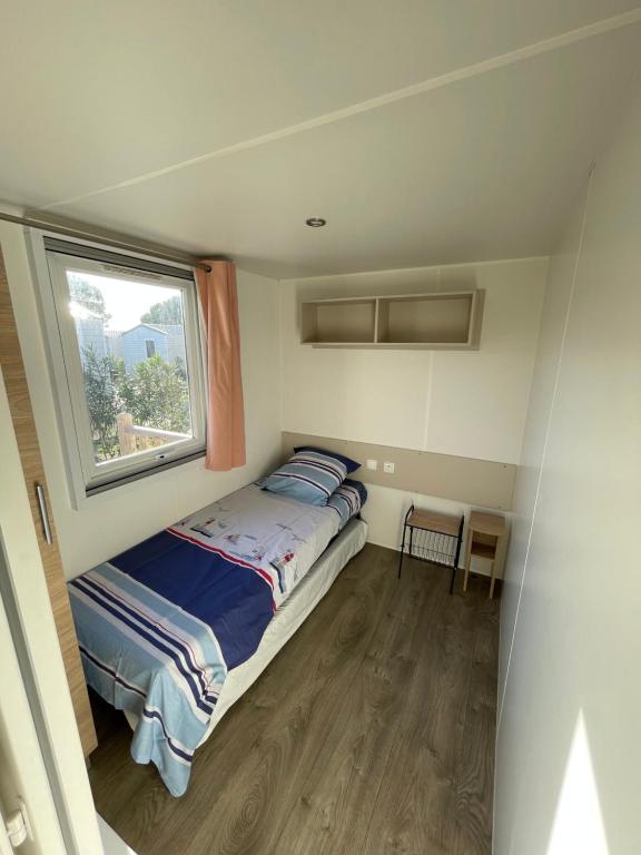 a small bedroom with a bed and a window at Mobil home 6 à 8 personnes Sans Fun Pass in Canet-en-Roussillon