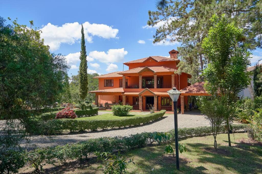 a large orange house with a garden in front of it at Fantastic Harmony Chalet in Pinar del Sol in Jarabacoa