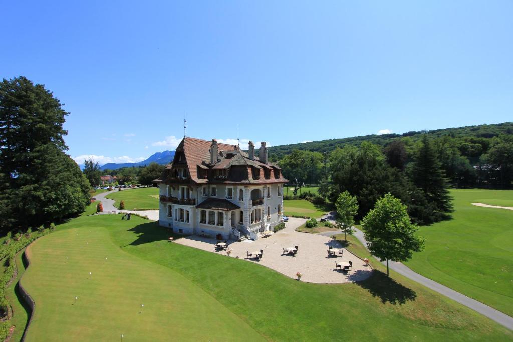 une vue aérienne sur une grande maison sur un champ verdoyant dans l'établissement Le Manoir du Golf, à Publier