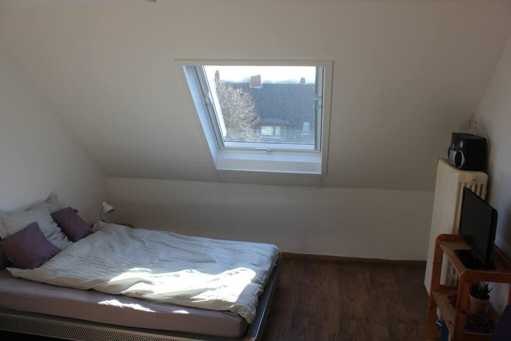 Dormitorio pequeño con cama y ventana en Ruhige Dachgeschosswohnung en Seelze