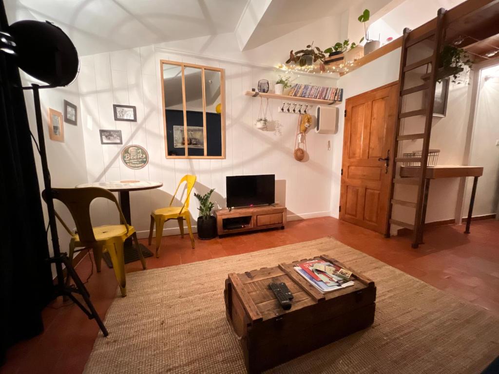 sala de estar con mesa, TV y mesa en Cosy Provençal, en Belgentier