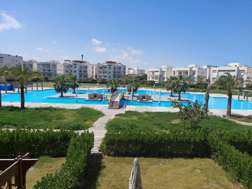 vistas a una piscina con palmeras y edificios en Amwaj North coast chalet in 1st floor families only en El Alamein