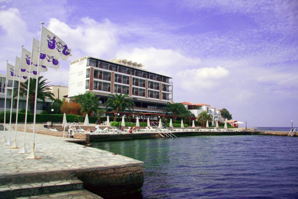 un bâtiment arborant des drapeaux devant une masse d'eau dans l'établissement Spetses Hotel, à Spetses