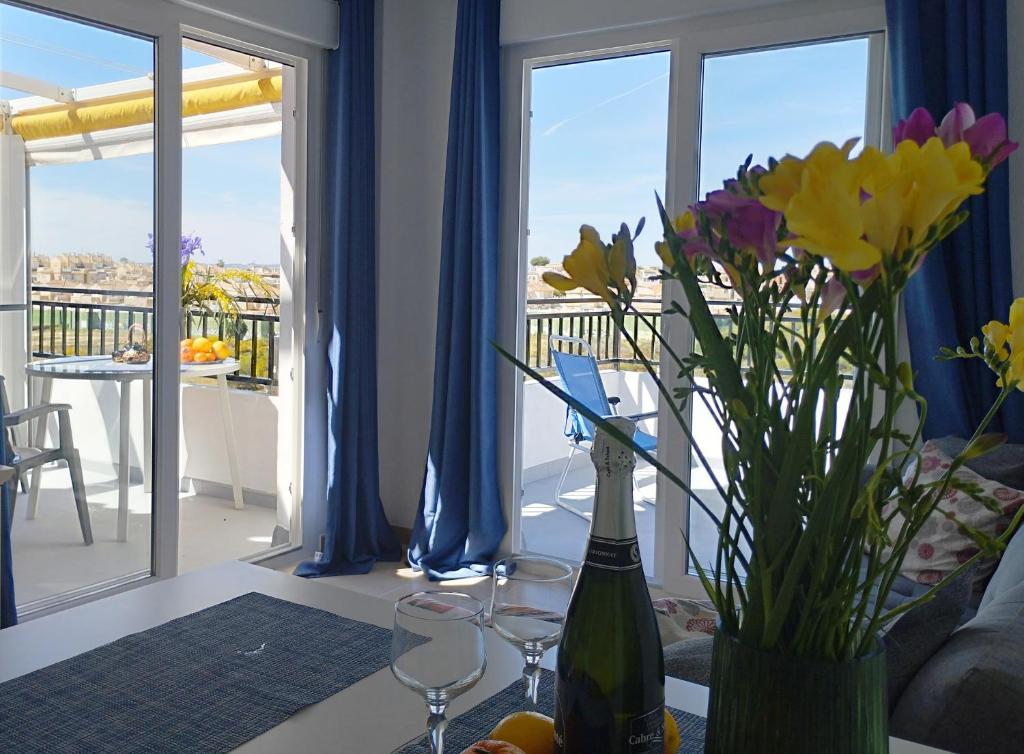 une table avec un vase de fleurs et des verres à vin dans l'établissement Sunny apartment with 2 terraces, à Torrevieja