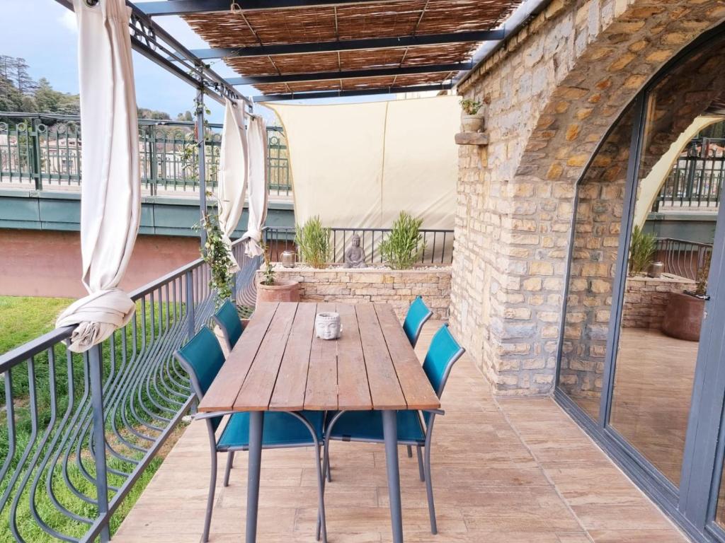 y balcón con mesa y sillas de madera. en La terrasse du Roubion, en Montélimar
