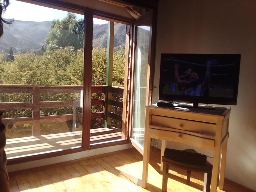 une télévision sur une commode devant une fenêtre dans l'établissement VF CATEDRAL, à San Carlos de Bariloche