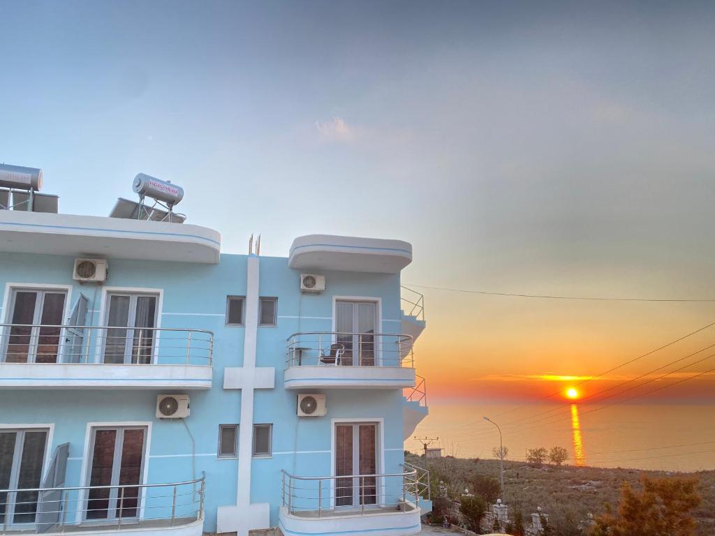 a building with the sunset in the background at Vila Llaka in Himare