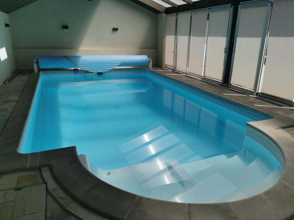 una grande piscina con acqua blu in un edificio di Gîtes Le P'tit Paradis du Ried a Sundhouse