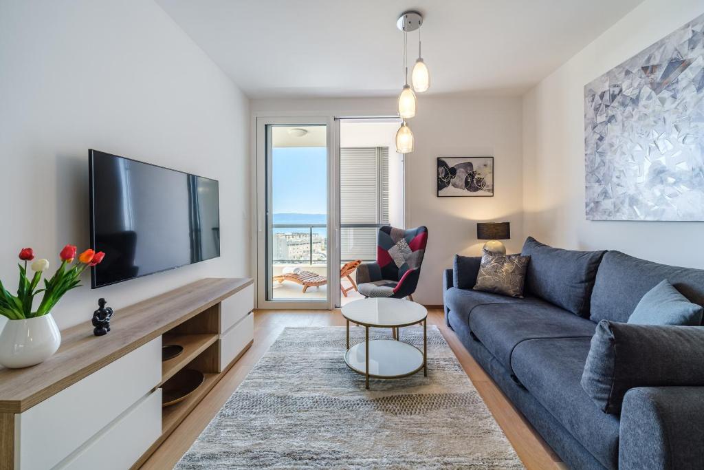 ein Wohnzimmer mit einem blauen Sofa und einem TV in der Unterkunft Golden view 7 in Split