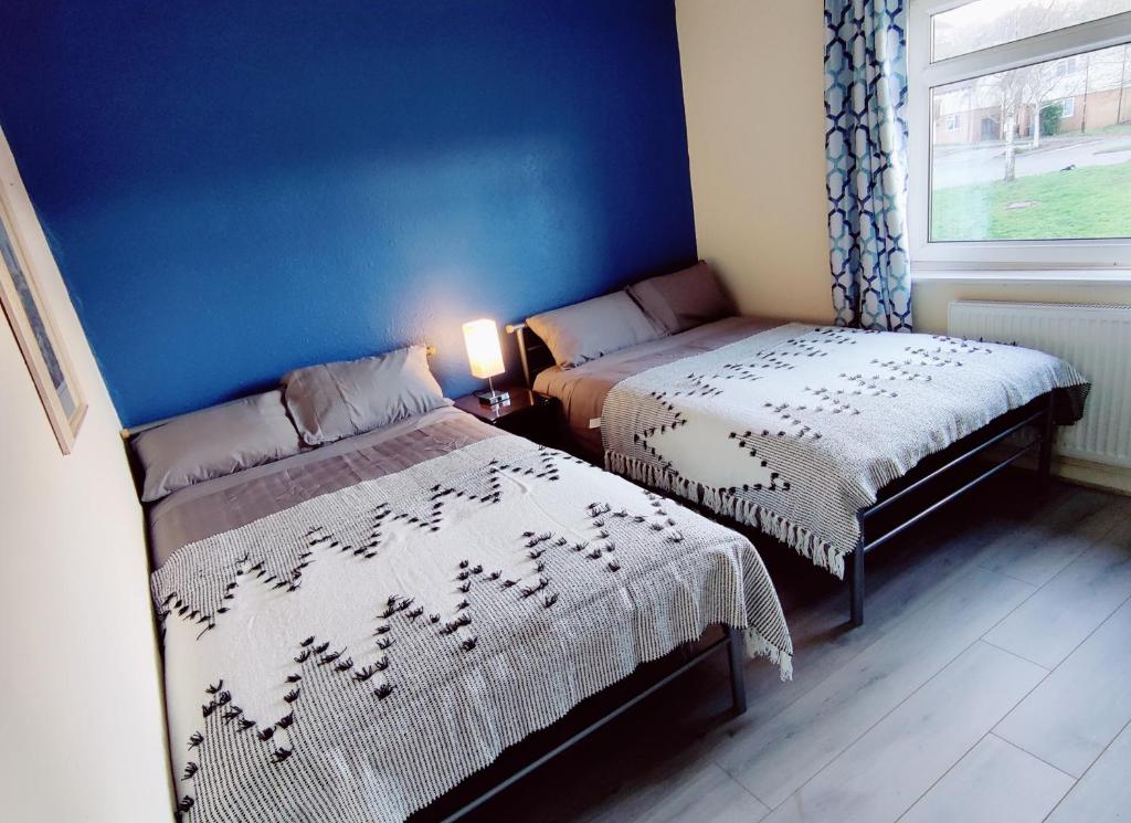 1 dormitorio con 2 camas y pared azul en Sherlock's house - 4 spacious bedroom 8 beds Private free parking & WIFI Accessibility Contractors Family with children & pets welcome en Burton upon Trent