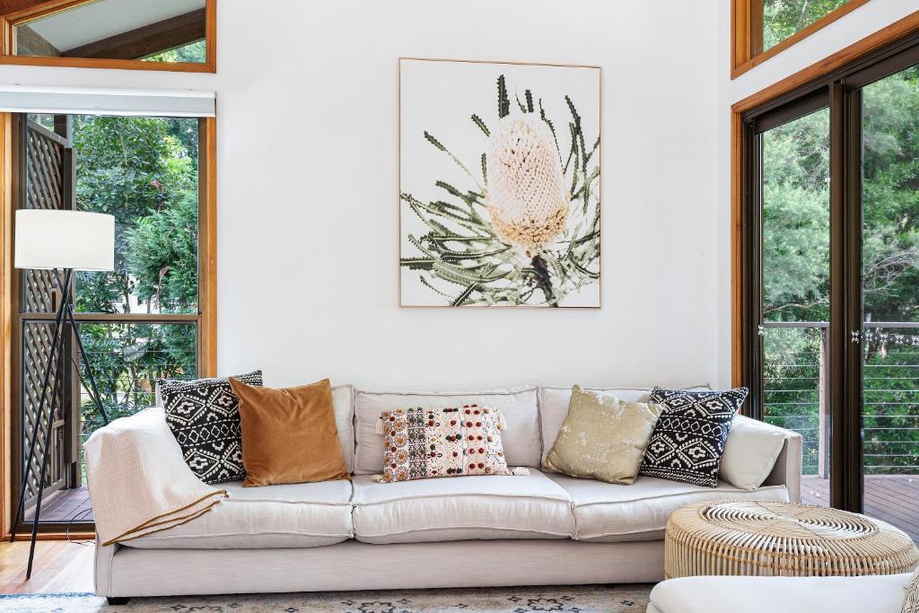 uma sala de estar com um sofá branco com almofadas em Hinterland family getaway em Maleny