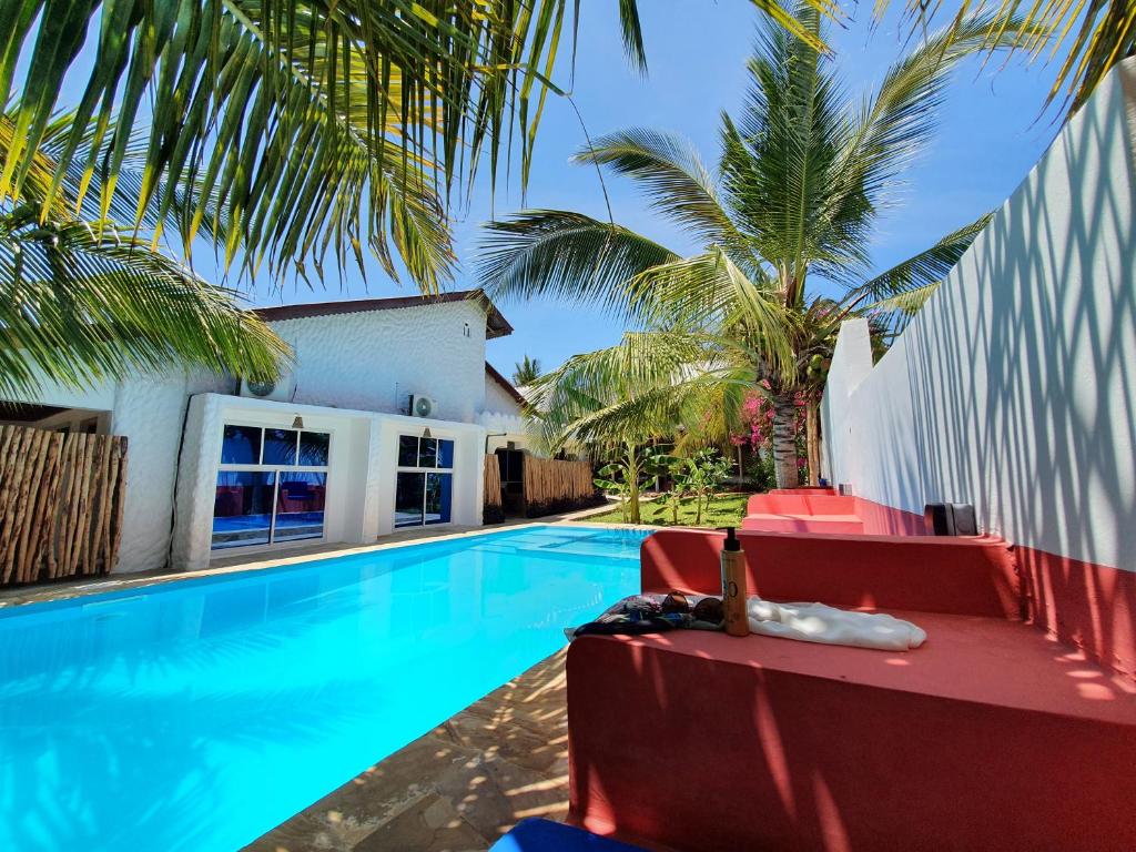 a swimming pool with red chairs and palm trees at BARIDI VILLA in Zanzibar City