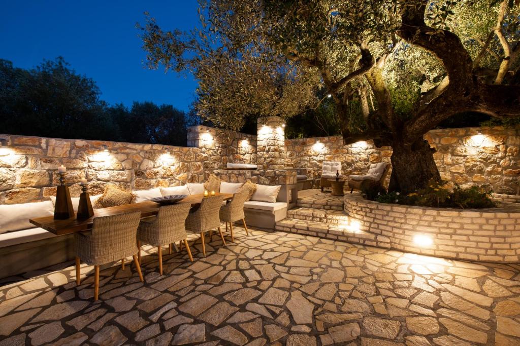 eine Terrasse mit einem Tisch und Stühlen sowie eine Steinmauer mit Licht in der Unterkunft Olivea Premium Holiday Homes in Stavros