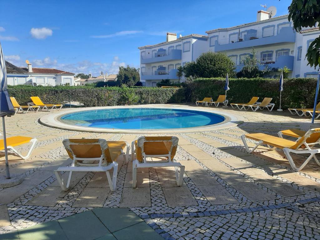 uma piscina com espreguiçadeiras e uma mesa e cadeiras em Sonho de férias em Portimão