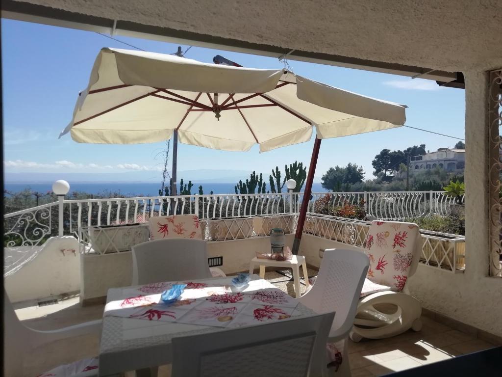 une terrasse avec une table et un parasol dans l'établissement Villetta La Scialuppa Capo Vaticano, à Capo Vaticano