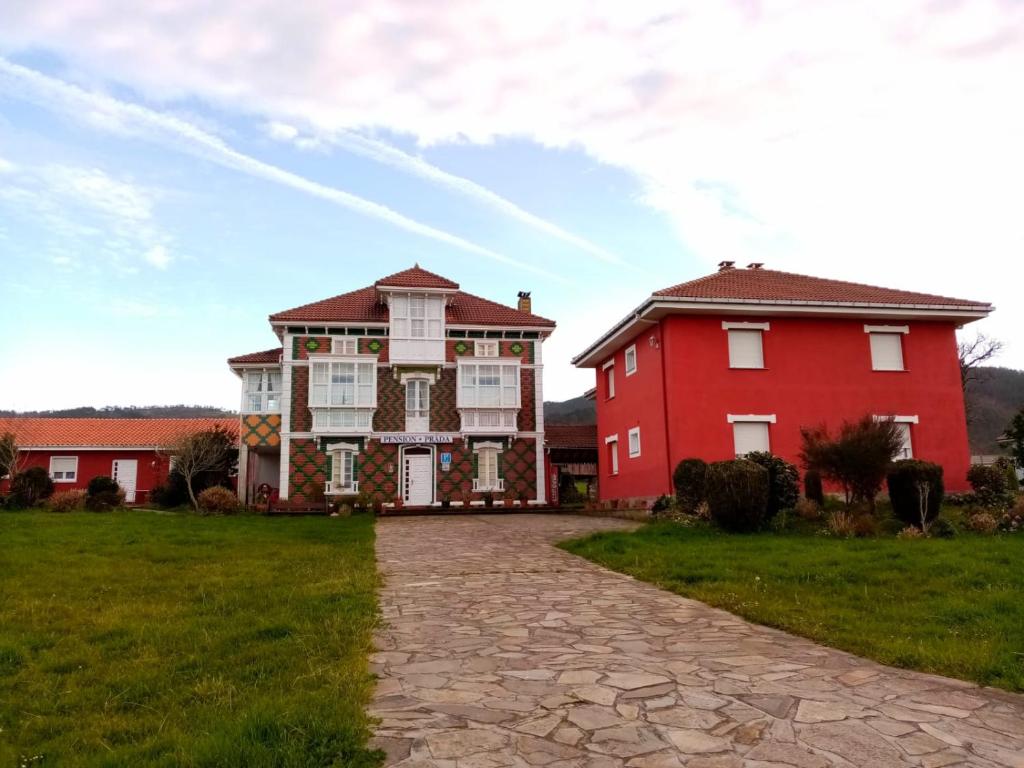 uma casa grande e um edifício vermelho num campo de relva em Alojamientos Prada em Ballota