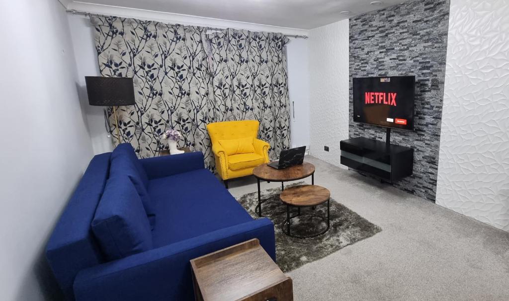 a living room with a blue couch and a yellow chair at Spacious Large House - Very close to M1 - Walking distance to L&D Hospital - Contractor Friendly - Large groups in Luton